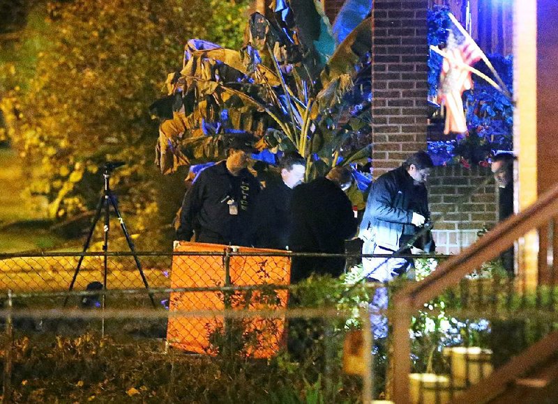 Police officers inspect the scene in St. Louis where a suspect died in a shootout with police early Monday. The man was suspected of shooting a police officer, one of several shootings of law enforcement officers in recent days.