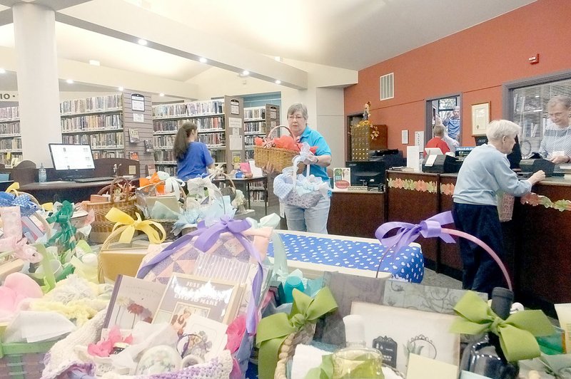 Lynn Atkins/The Weekly Vista Members of the Friends of the Bella Vista Library arrange gift baskets for the annual silent auction last week. The auction lasts until December 10 and is one of the groups best fundraisers.