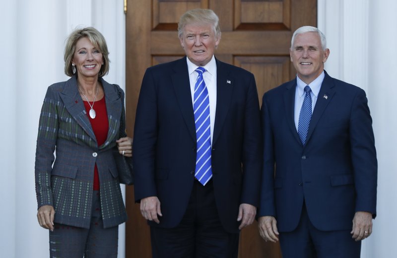 FILE - In this Nov. 19, 2016 file photo, President-elect Donald Trump, Vice President-elect Mike Pence and Betsy DeVos pose for photographs at Trump National Golf Club Bedminster clubhouse in Bedminster, N.J. Trump has chosen charter school advocate DeVos as Education Secretary in his administration. (AP Photo/Carolyn Kaster, File)
