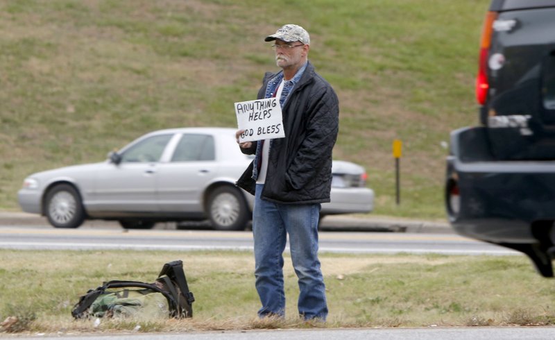 Kenny Foskitt asks for donations Tuesday as traffic passes by on the northbound exit of Interstate 49 near West Sunset Avenue in Springdale. 