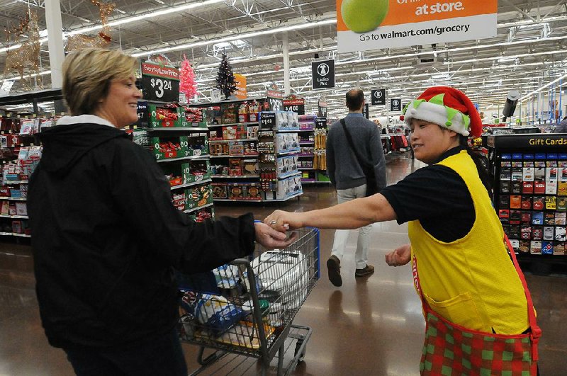 Theresa Johnston, a Wal-Mart holiday helper, hands out candy Tuesday to a customer in Rogers.
