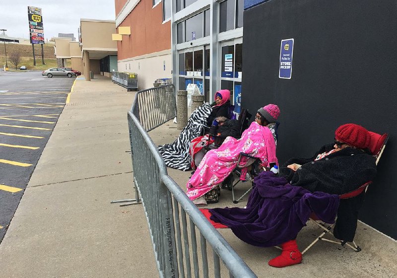 Early Black Friday shoppers hunker down in coats, hats and blankets outside a North Little Rock Best Buy on Thursday morning.