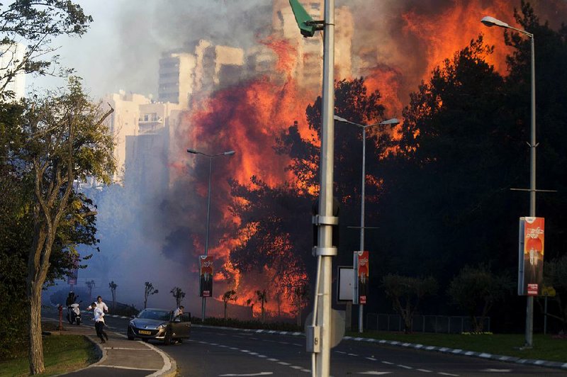 People scatter Thursday in Haifa, Israel, as a wildfire rages through the city. Thousands of people were forced to evacuate Haifa, the country’s third-largest city, because of the wildfire. Israeli officials have raised the possibility of terrorist links to the blaze. 