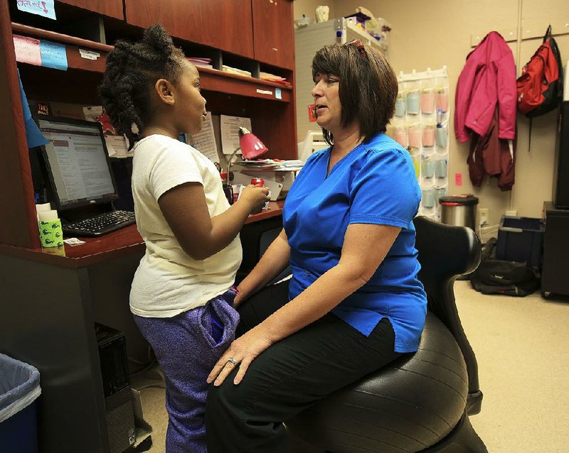 School nurse Ronda Wagner talks with McKenzie Clay, 5, in her office at Angie Grant Elementary School in Benton earlier this month. McKenzie was diagnosed with an ear infection through a telemedicine program.