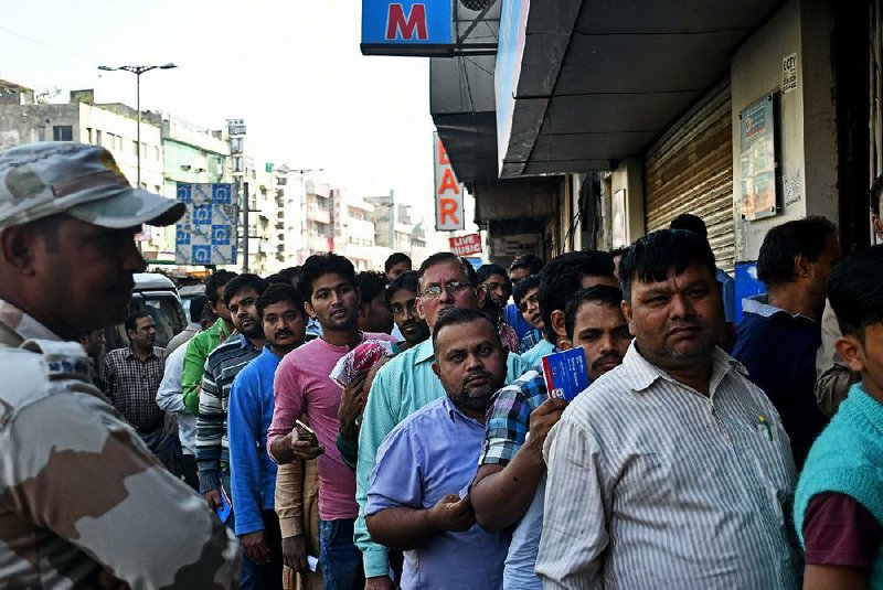 People wait outside a bank Friday in Delhi, India. Indians remain confused over the changing rules on bank notes. 