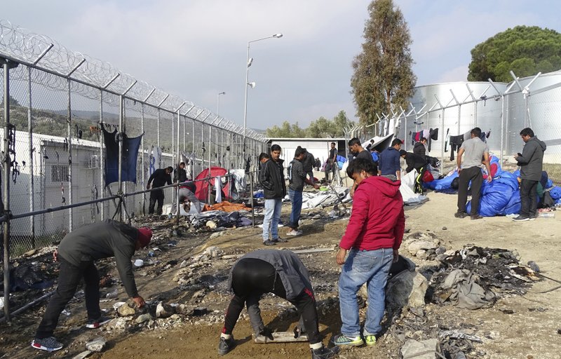 Refugees help clear the Moria refugee camp after a fire on the northeastern Greek island of Lesbos, on Friday, Nov. 25, 2016. 