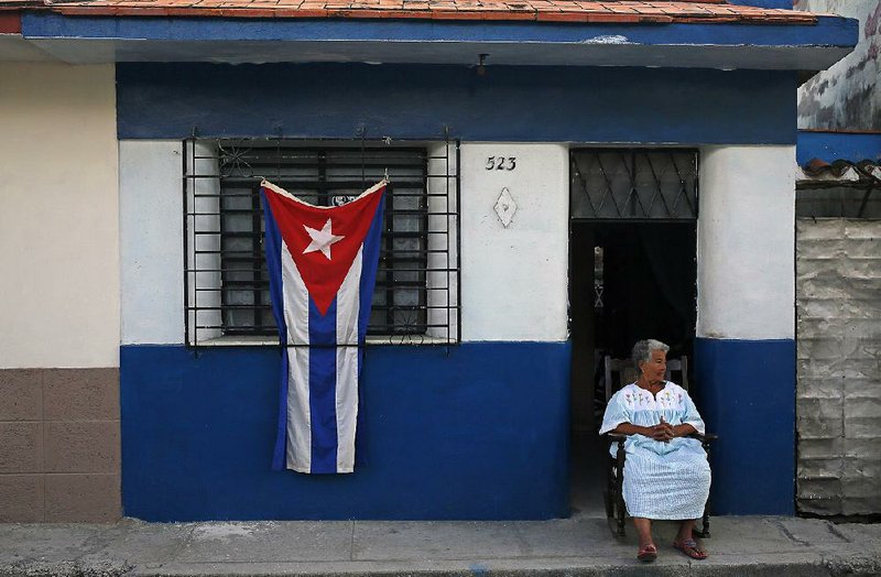 A woman sits in the doorway of her home, decorated with a Cuban flag in honor of the late Fidel Castro, in the town of Regla on the outskirts of Havana on Sunday.
