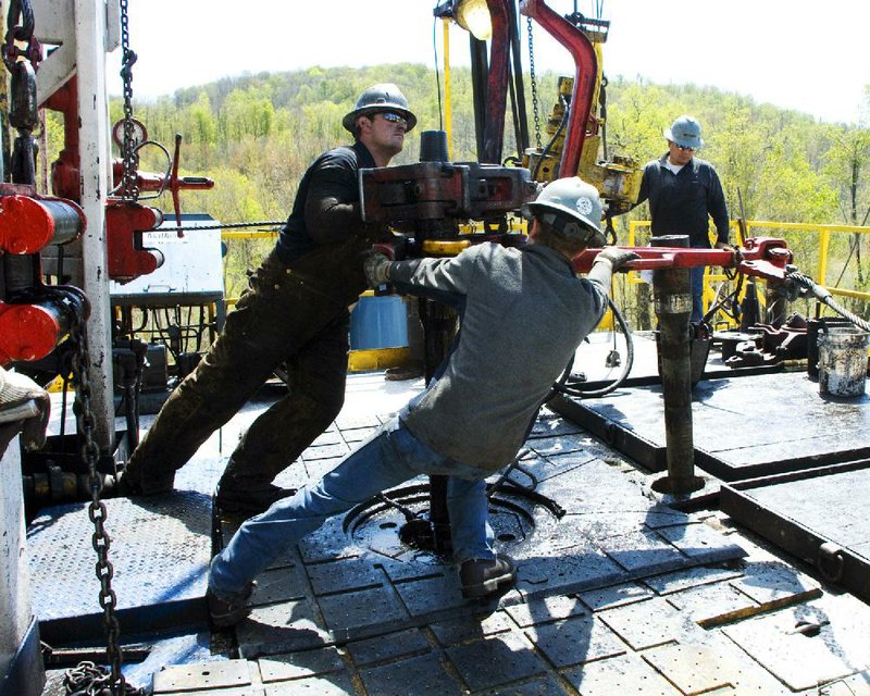 Workers wrestle a section of a well casing into place at the site of a Chesapeake Energy natural gas well near Burlington, Pa., in this file photo. Oil field services companies are starting to see more demand from drillers as crude and natural gas prices make drilling more profi table.
