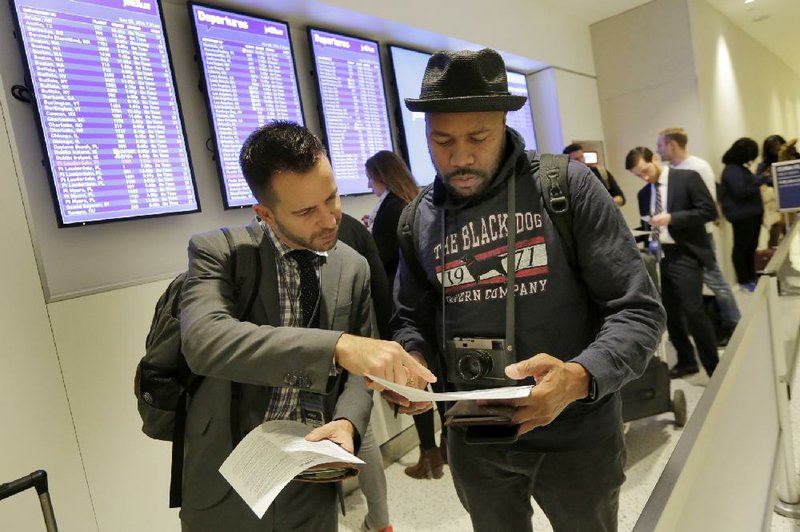 David McGraw (left) and Derrick Jones, both of New York, look over their paperwork Monday while waiting to check in for JetBlue’s inaugural fl ight from John F. Kennedy International Airport to Havana.