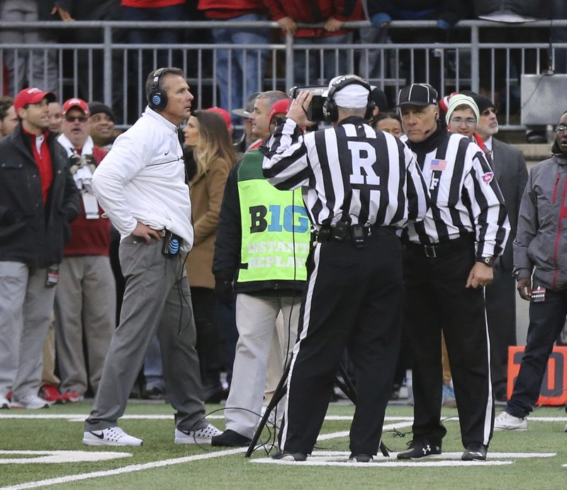 Officials review a fourth down spot as Ohio State head coach Urban Meyer paces the sidelines during overtime of an NCAA college football game against Michigan, Saturday, Nov. 26, 2016, in Columbus, Ohio. Ohio State beat Michigan 30-27 in double overtime. 