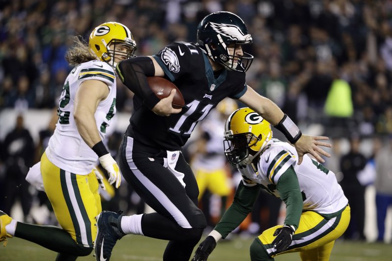 Philadelphia Eagles' Carson Wentz, center, scrambles past Green Bay Packers' Damarious Randall, right, and Clay Matthews during the first half of an NFL football game, Monday, Nov. 28, 2016, in Philadelphia. 