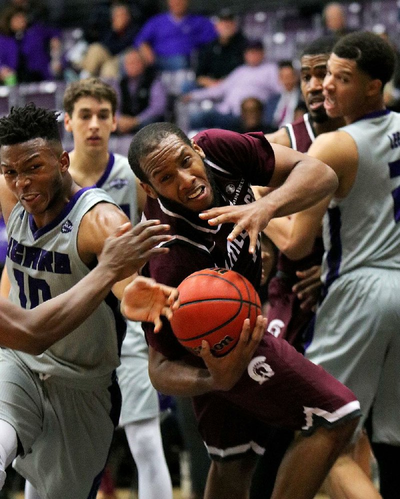 UALR’s Maurius Hill (center) and Central Arkansas’ Mathieu Kamba scrap for a loose ball during the second half of Tuesday night’s game at the Farris Center in Conway. After trailing by 12 points in the second half, UCA rallied to force overtime. But UALR won 89-87 in overtime.