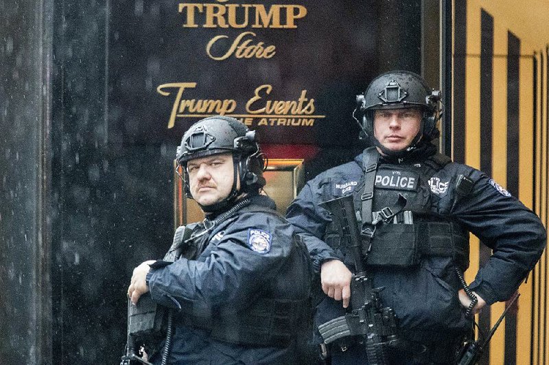 New York police officers stand guard in the rain Tuesday outside Trump Tower as transition efforts continue inside.