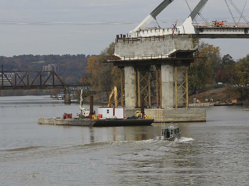 A barge floats Tuesday on the Arkansas River, where explosives were used last week to demolish a footing from the old Broadway Bridge. Continued work on the demolition of the footing will delay the placing of the second arch for the new bridge, which had been scheduled for today.