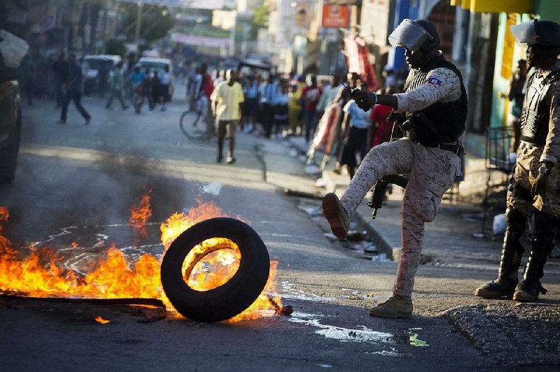 A national police officer removes a tire set ablaze by supporters of presidential candidate Maryse Narcisse of the Fanmi Lavalas political party on Monday in Port-au-Prince, Haiti.