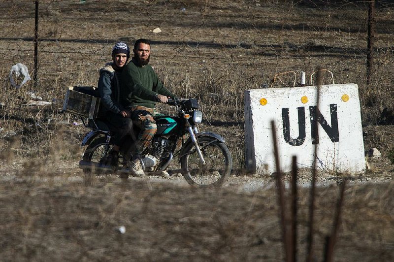 Two men ride toward an abandoned U.N, base Monday at Syria’s Quneitra border crossing across from the Israel-controlled Golan Heights.