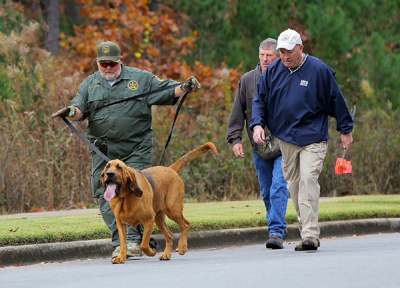 Frank Hurst, with Bloodhound Man Trackers, and his dog Radar walk Tuesday with Little Rock police detectives Greg Siegler and Tommy Hudson (right) as they search an area around Chalamont Park in Little Rock for Ebby Steppach, who was 18 when she disappeared in October 2015.