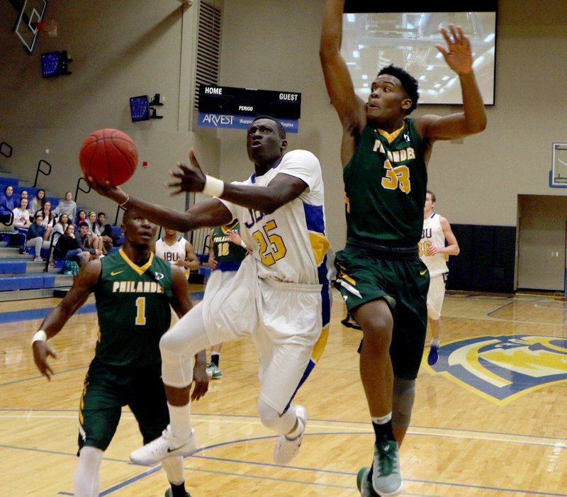 Photo courtesy of JBU Sports Information John Brown University junior Samuel Egedi drives to the basket as Philander Smith forward Justin Small, right, and guard Jamahl Jackson defend during Monday&#8217;s game at Bill George Arena. The Golden Eagles defeated the Panthers 93-67.