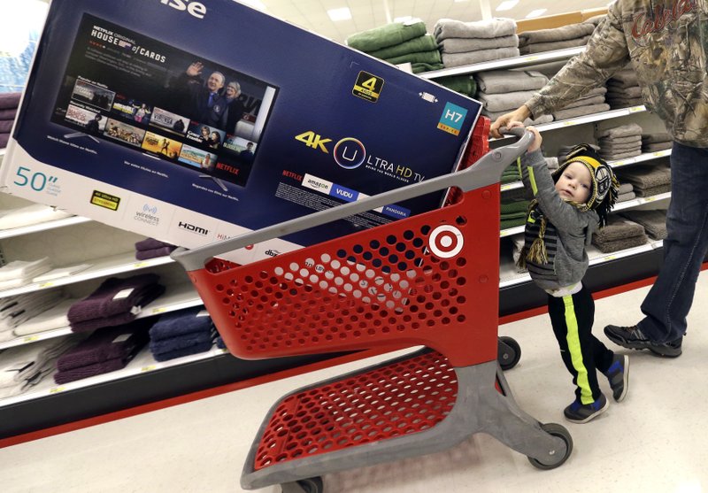 In this Friday, Nov. 25, 2016, file photo, Hunter Harvey, 2, helps his dad, C.J., wheel a big screen TV at Target, in Wilmington, Mass.  