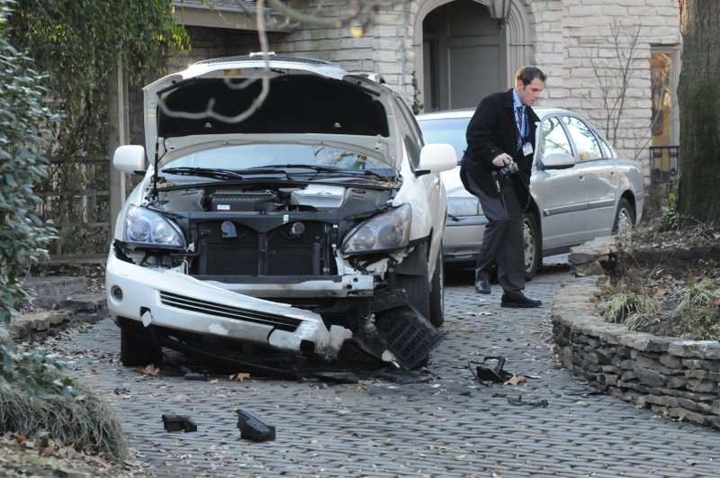  In this Feb. 4, 2009 file photo, a West Memphis, Ark., police detective surveys the damage after a car owned by Trent Pierce, chairman of the Arkansas Medical Board, exploded as he was leaving home. 