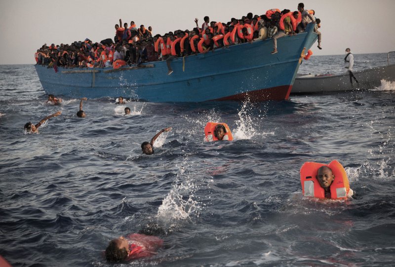 In this Aug. 29, 2016 file photo, migrants, most from Eritrea, jump into the water from a crowded wooden boat as they are helped by members of a nongovernmental organization during a rescue operation in the Mediterranean Sea, about 13 miles (20 kilometers) north of Sabratha, Libya. 