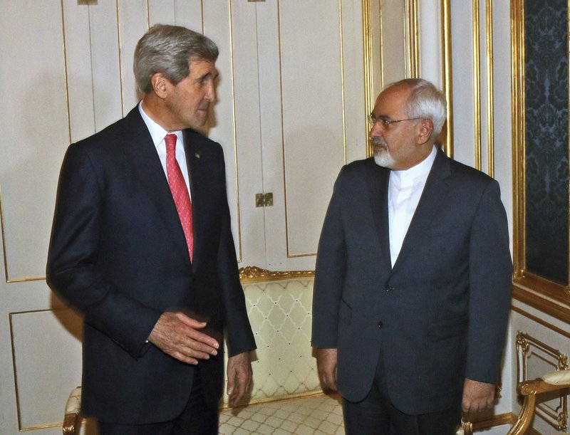 In this Nov. 23, 2014 file-pool photo, Secretary of State John Kerry talks with Iranian Foreign Minister Mohammad Javad Zarif in Vienna, Austria. Kerry plans to see Zarif this week amid Iranian complaints that it's not getting the sanctions relief it deserves under last year's landmark nuclear deal. 