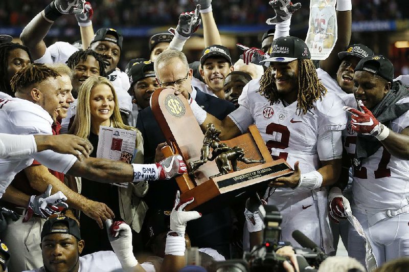 Alabama quarterback Jalen Hurts (2) hands the SEC championship trophy to teammates after the top-ranked Crimson Tide’s 54-16 victory over No. 15 Florida on Saturday in Atlanta.