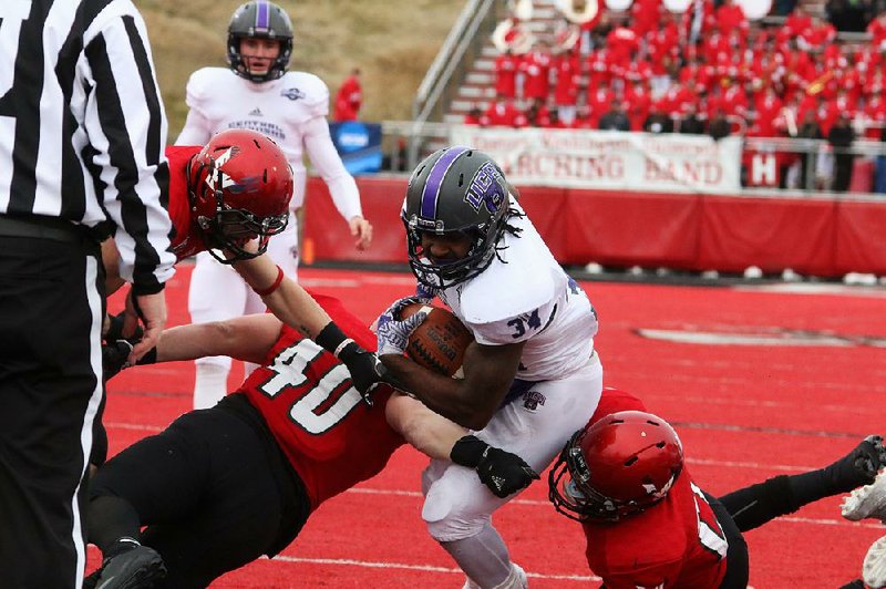 Central Arkansas running back Antwon Wells (center) squeezes by three Eastern Washington defenders for a touchdown in the second round of the Football Championship Subdivision playoffs Saturday at Roos Field in Cheney, Wash. Eastern Washington overcame a 14-point defi cit to beat the Bears 31-14.