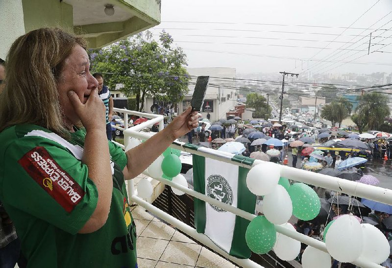 An onlooker films as trucks carrying coffins with the remains of Chapecoense soccer club members, victims of a plane crash in Colombia, drive through the streets of Chapeco, Brazil, on Saturday.