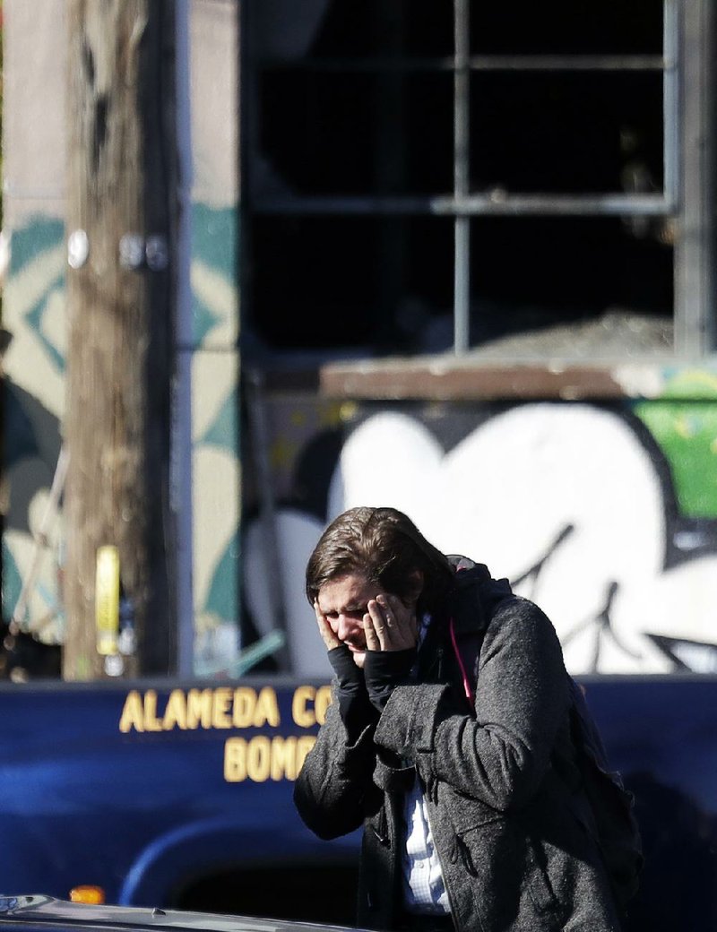 A man covers his face in anguish Saturday near the scene of a fi re at a converted warehouse in Oakland, Calif. Several people died, and officials said more bodies were trapped in the debris.