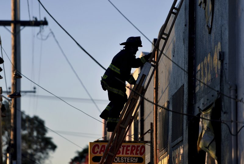 A firefighter climbs a ladder after a deadly fire at a warehouse rave party in Oakland, Calif., earlier in the morning on Dec. 3, 2016.