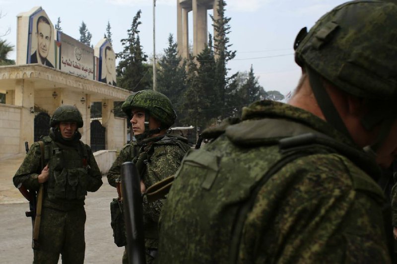 Russian soldiers stand next to an aid convoy Sunday in Aleppo, Syria. The Syrian army says it has retaken more than half of the districts held by rebels in eastern Aleppo.