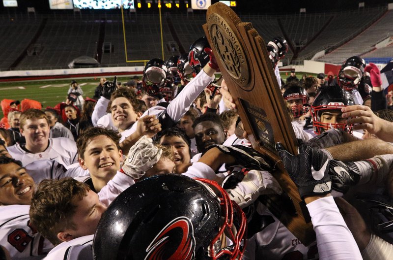 Russellville players celebrate with the championship trophy after defeating Greenwood in the Class 6A championship game Saturday night at War Memorial Stadium in Little Rock. The Cyclones claimed their first state title since the Arkansas Activities Association instituted its modern playoff system in 1968.