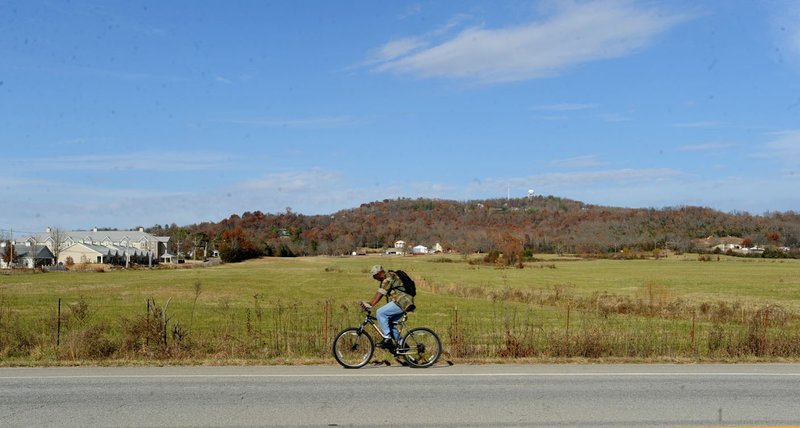 A cyclist rides Friday near Morningside Drive and 15th Street in Fayetteville. Rausch Coleman Homes will develop a 290-lot Park Meadows subdivision on the 68-acre site. Developers expect to kick up dirt on the project by mid-2017