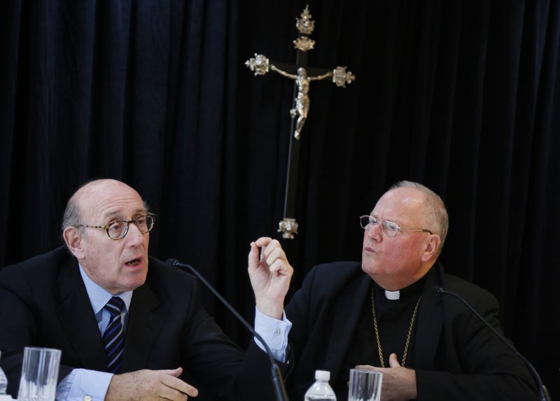 FILE - In this Oct. 6, 2016 file photo, Cardinal Timothy Dolan, Archbishop of New York, right, listens as Kenneth Feinberg speaks to reporters during a news conference in New York announcing a new program intended to provide reconciliation and compensation for victims of sexual abuse by clergy. 