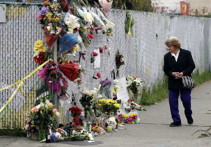 A woman walks past a makeshift memorial Monday near the site of a warehouse fire in Oakland, Calif.