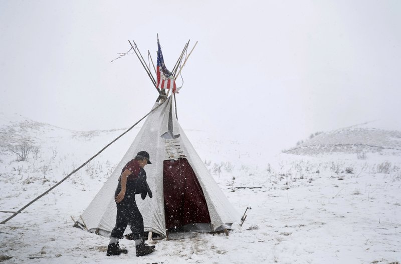 Vietnam veteran Allen Coomsta Matt walks into his teepee at the Oceti Sakowin camp where people have gathered to protest the Dakota Access oil pipeline as snow begins to fall in Cannon Ball, N.D., Monday, Dec. 5, 2016. 