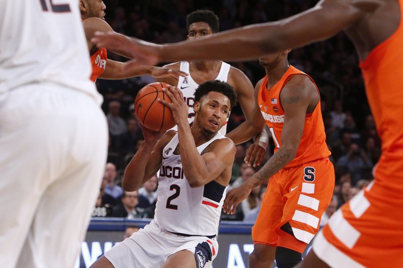 The Associated Press SEA OF ORANGE: Connecticut's Jalen Adams (2) handles the ball in traffic against Syracuse during the first half of the Huskies' 52-50 win over Syracuse Monday in New York.