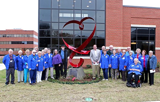 The Sentinel-Record/Richard Rasmussen HEART OF NPMC: NPMC Auxiliary volunteers gather with artists Bre Harris and David Harris, nearest the sculpture, titled “The Heart of National Park Medical Center,” on left, and president of the RCCH Arkansas market, Jerry Mabry, closest to statue on right, after the dedication ceremony Monday.