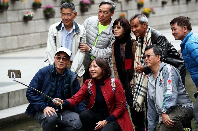 Tourists pose for a group photo taken with a Samsung Galaxy smartphone at the Cheonggyecheon Stream, a river walk in Seoul, South Korea, in October. A unanimous U.S. Supreme Court ruled Tuesday that Samsung may not have to pay all of a $399 million judgment for copying parts of Apple’s iPhone. 