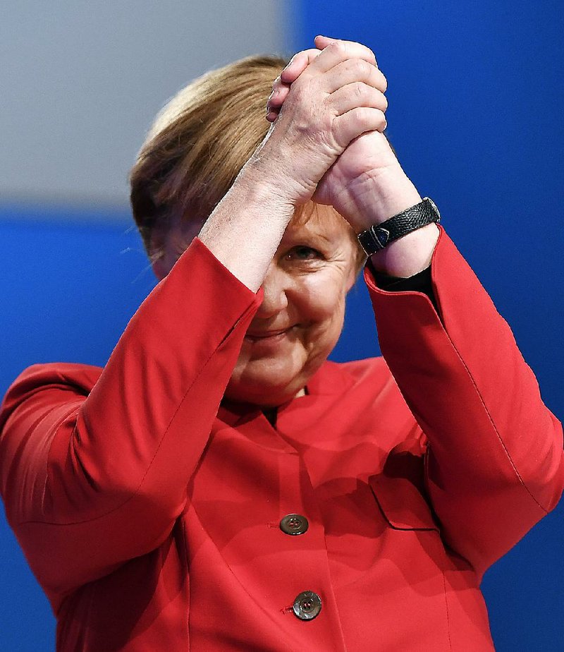 German Chancellor Angela Merkel acknowledges applause after a speech Tuesday at her party’s convention in Essen, Germany. Merkel, who is seeking a fourth term, reached out to critics of her immigration policy with a call for banning full-face veils and a promise to limit future refugee waves. 