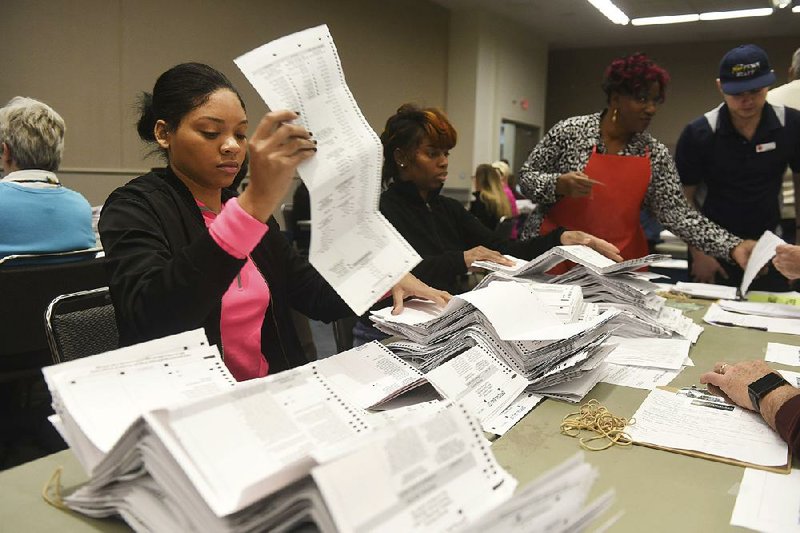 Election worker Summer Stewart and other staff members in Detroit check through presidential ballots Tuesday that were cast in Wayne County, Mich. The recount could be stopped today.