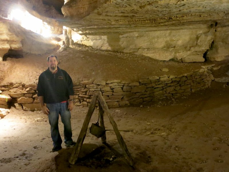 Photo by Susan Holland Paul Linscott, owner of the Old Spanish Treasure Cave in Sulphur Springs, poses in the cave&#8217;s Council Room beside campfire artifacts left by previous owner George Dunbar. Paul and his wife Tracy have recently begun screening movies in the Council Room, and their guests have been delighted with the shows. The Linscotts also offer caving nights for Scouts and youth groups.