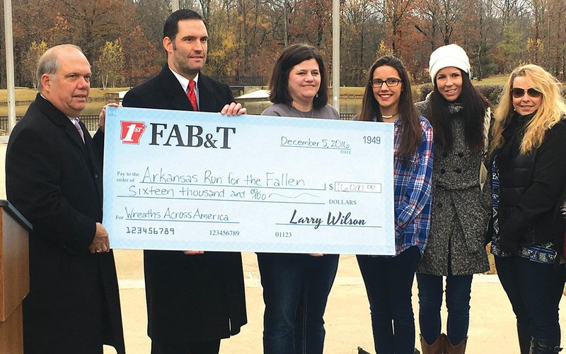From left, Larry Wilson, CEO of First Arkansas Bank and Trust; Mark Wilson, senior vice president at First Arkansas Bank and Trust; Angela Beason, treasurer of Arkansas Run for the Fallen; Ariana Ramirez; Jennifer Legate; and Barbara Kordsmeier, pose with a check for $16,000 that First Arkansas Bank & Trust donated to help provide wreaths for every headstone at the Arkansas State Veterans Cemetery in North Little Rock this year. Ramirez, Legate and Kordsmeier are relatives of military service members who have died