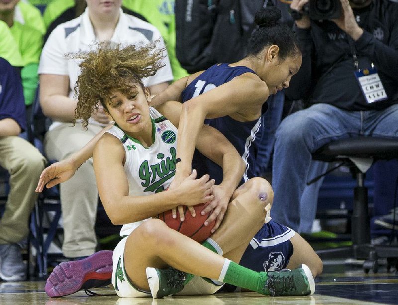 Notre Dame’s Mychal Johnson (left) fights for a loose ball with Connecticut’s Saniya Chong during Wednesday night’s game.