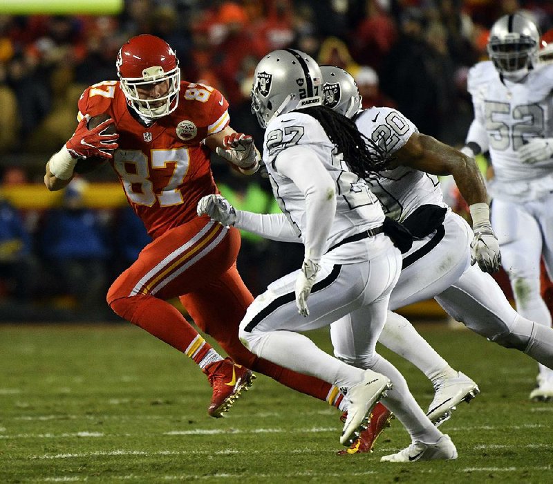 Kansas City tight end Travis Kelce (left) runs away from Oakland defenders in the first half of Thursday night’s game in Kansas City, Mo. Kelce had fi ve catches for 101 yards to help the Chiefs move into a tie for first place in the AFC West with a 21-13 victory.