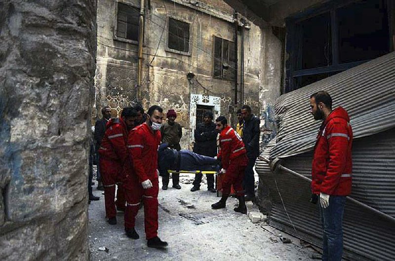 Syrian Arab Red Crescent workers carry a patient out of a facility in Aleppo’s Old City. Relief agencies said 148 people were evacuated Wednesday at the facility after fi ghting had calmed.