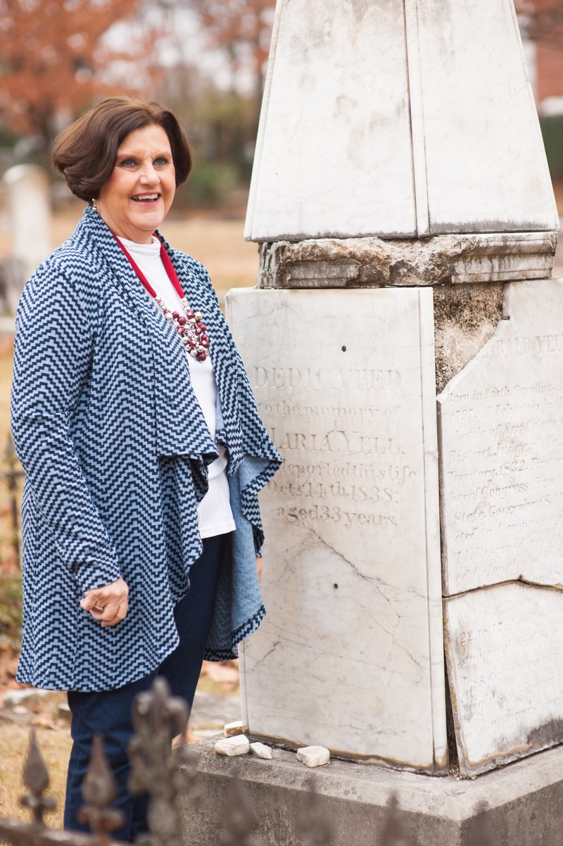 Evergreen Cemetery Association President Marilyn Heifner stands beside the damaged headstone of Archibald Yell. Proceeds from “History Comes Alive” will help pay for a new monument to mark Yell’s grave.