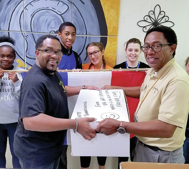 Submitted photo Hot Springs World Class High School students, back, from left, Sonora Bolton, Kaleb Hughley, Elizabeth Strasemeiere, Olivia McCafferty and Mary Rice worked with their classmates in the French Club to raise funds to purchase a Thanksgiving turkey dinner for a family in need. Faculty adviser Clyde Hughley, left, recently presented the donation to Lavon Chatman, New Faith Christian Ministries.