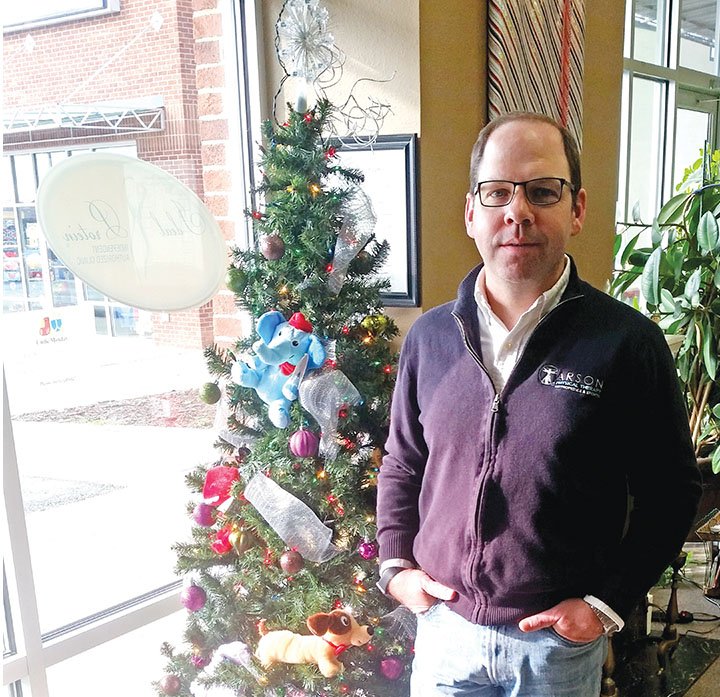 Adam Carson of Carson Physical Therapy stands in front of the tree at his office in Bryant. Carson hosts an annual Christmas Potluck and Toy Drive.